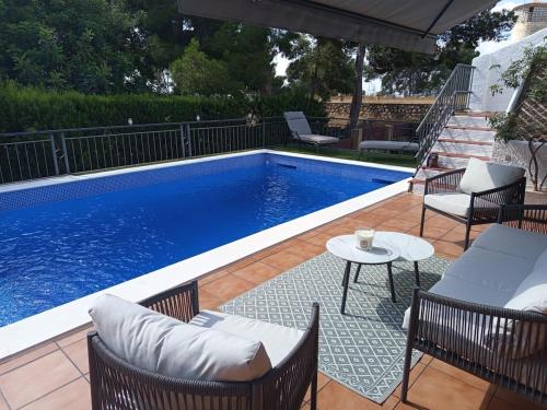 a swimming pool with chairs and a table next to it at Casa Azahar in Lliria