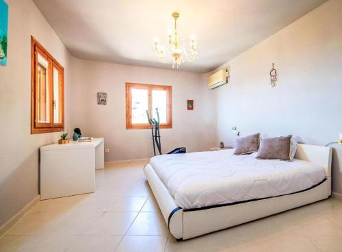 a bedroom with a large white bed and a chandelier at Altea Hills Best Seaview in Altea