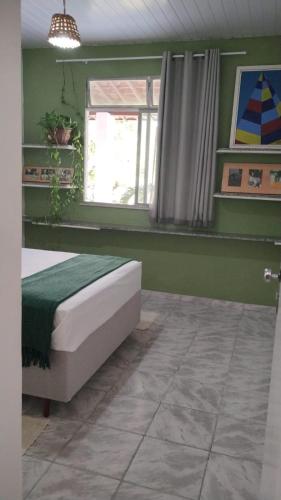 a green bedroom with a bed and a window at Quarto privativo em casa compartilhada in Aracaju