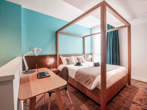 a bedroom with a bed and a desk with a laptop at ibis Styles La Rochelle Centre Vieux Port in La Rochelle