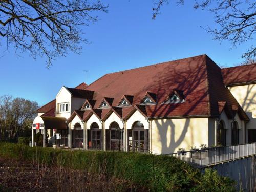 a large white building with a brown roof at Hôtel Ibis Nevers in Nevers