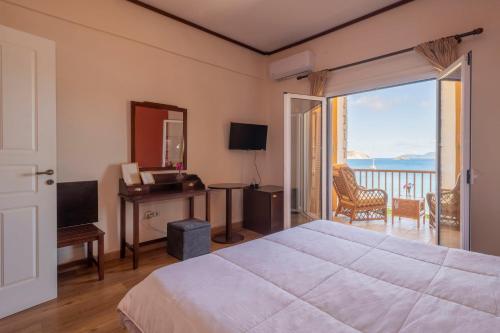 a bedroom with a bed and a desk and a balcony at Methoni Beach Hotel in Methoni