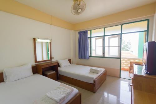 a bedroom with two beds and a tv and a window at Mont Talay Hotel in Prachuap Khiri Khan