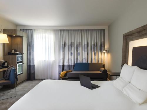 a hotel room with a bed and a couch at Novotel Ipswich Centre in Ipswich