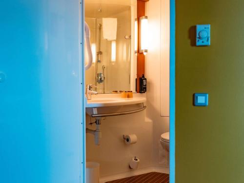 a bathroom with a sink and a mirror and a toilet at ibis Marseille Provence Aéroport in Marignane