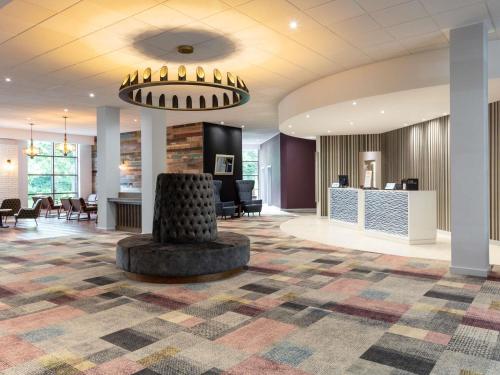 a lobby with a large room with a table and chairs at Novotel Newcastle Airport in Newcastle upon Tyne