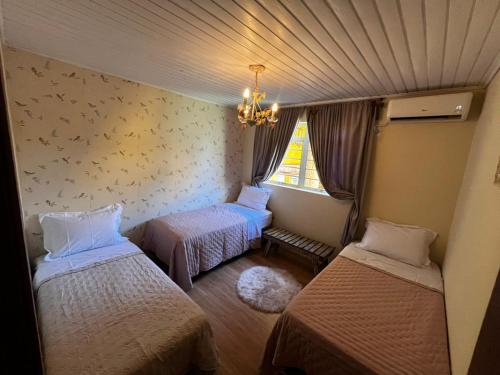 a room with two beds and a chandelier at Casa Conforto & Lazer Foz do Iguaçu in Foz do Iguaçu