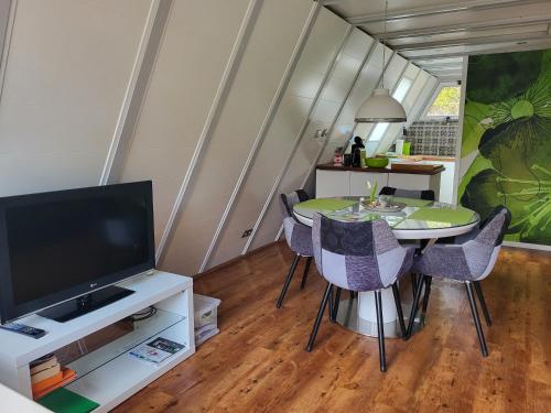 a dining room with a table with chairs and a television at Nurdachhaus Ferienpark Schellbronn in Schellbronn