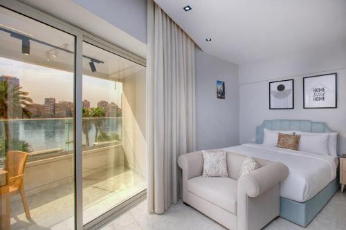 a bedroom with a bed and a chair and a window at Cairo Homes Nile View Studios Manial in Cairo