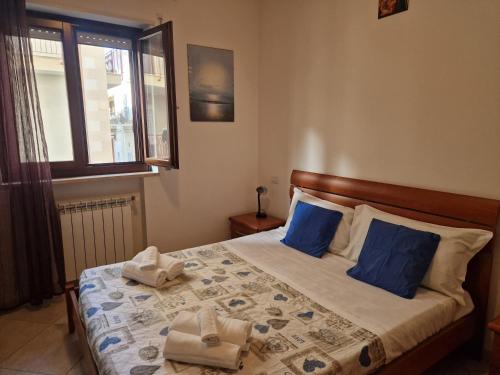 a bedroom with a bed with blue pillows and a window at Cavalluccio Marino-Central-with Balcony by Gessica Holiday in Polignano a Mare
