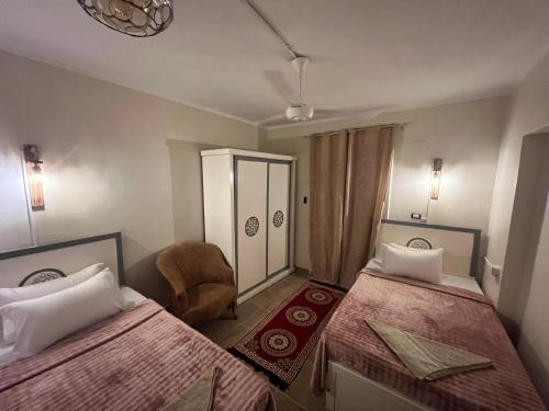 a hotel room with two beds and a chair at Backpacker Room 2 in Aswan