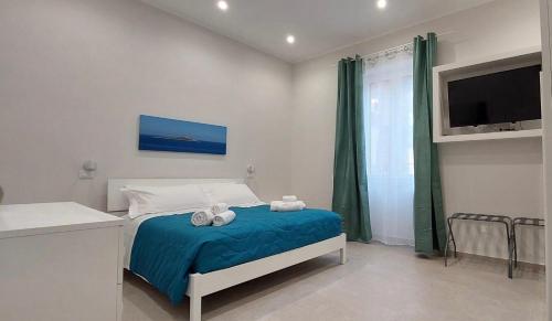 a bedroom with a bed with blue sheets and a tv at Halisa Casa Vacanze in Palermo