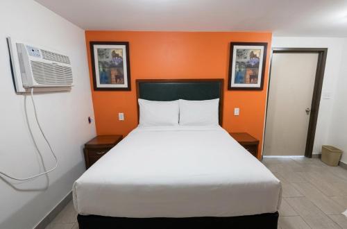 a bedroom with a white bed and an orange wall at GG Rest-Inn in Elizabeth