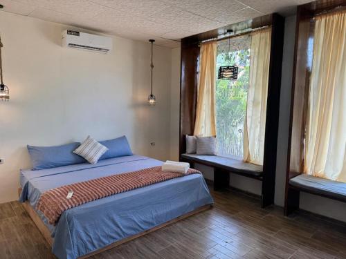 a bedroom with a bed with blue sheets and a window at Villa Monarca in Ayampe