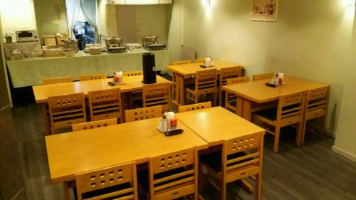 市原市にあるホスピタリティイン 八幡宿の木製のテーブルと椅子が備わる空きレストランです。