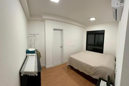 a bedroom with a bed and a table in it at APARTAMENTO PRÓXIMO AO CENTRo in Joinville