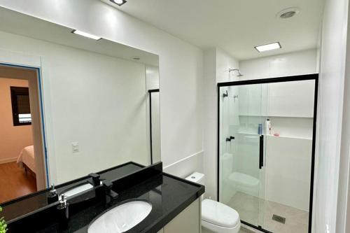 a bathroom with a sink and a toilet and a mirror at APARTAMENTO PRÓXIMO AO CENTRo in Joinville