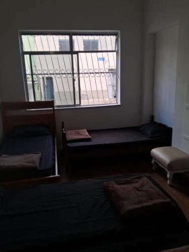 a room with a window with a bed and a chair at Pousada Paula Lima I in Juiz de Fora