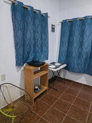 a room with blue curtains and a table and a fan at Estudio Mar in Brisas de Zicatela