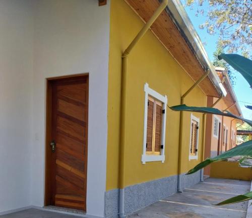 a yellow and white house with a wooden door at Recanto do Ipê in Extrema