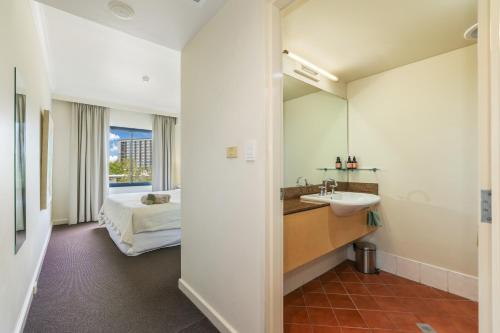 a bathroom with a sink and a bed and a mirror at Spacious Darwin Esplanade Retreat with Pool & Spa in Darwin