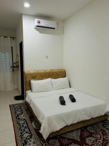 a bedroom with a bed with two shoes on it at Homestay D'Aina in Teluk Intan