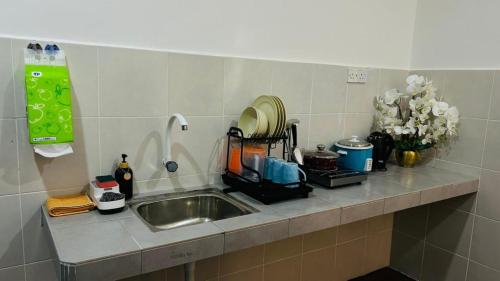 a kitchen counter with a sink and flowers on it at Homestay D'Aina in Teluk Intan