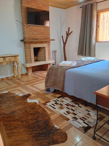 a bedroom with a bed and a fireplace at Chalé vale do Monte Verde in Camanducaia