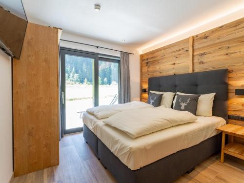 a bedroom with a large bed and a large window at Pinzgau Lodge 2E in Wald im Pinzgau