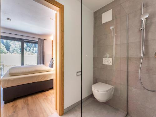 a bathroom with a shower and a toilet and a bed at Pinzgau Lodge 2E in Wald im Pinzgau