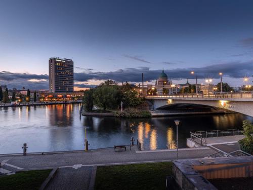 a bridge over a river with a city at night at Mercure Hotel Potsdam City in Potsdam