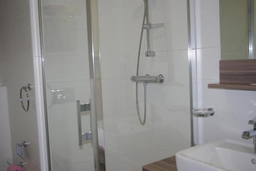 a shower with a glass door next to a sink at Auberge de Marville in Marville