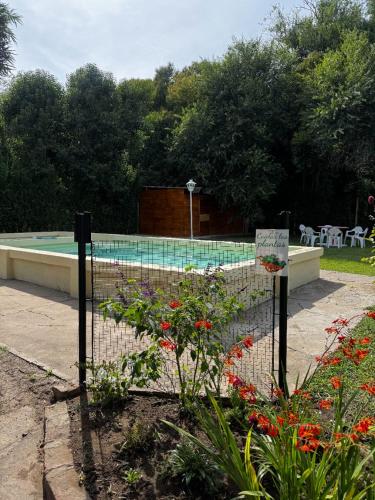 a fence with flowers in front of a swimming pool at Quinta La Soñada eventos luján in Luján