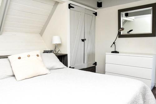 a bedroom with a white bed and a mirror at Mont Ste-Anne Chalet in Beaupré
