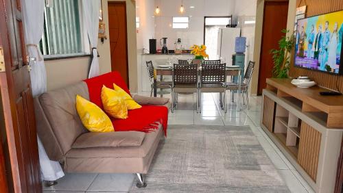 a living room with a red couch and a dining room at Casa de Temporada D'Amaro in Santo Amaro