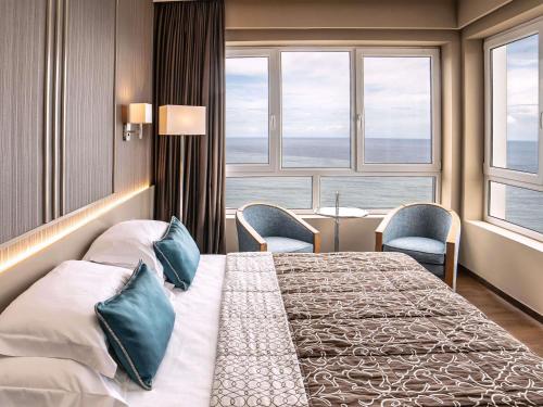 a hotel room with a large bed and windows at Mercure Monte Igueldo in San Sebastián