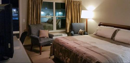 a hotel room with a bed and a chair and a window at Rolling Hills Lodge in Cherokee