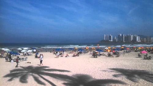 a group of people on a beach with umbrellas at Flat Capitania Varam Ap 3053 in Guarujá