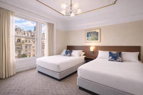 two beds in a hotel room with a window at Cornell Hotel Union Square in San Francisco