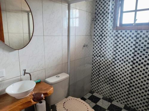a bathroom with a sink and a toilet and a mirror at Casa de Boneca in Campos do Jordão