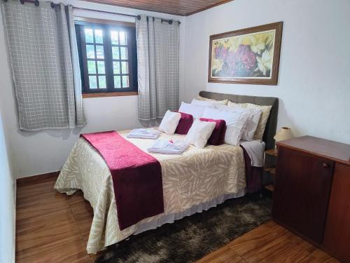 a bedroom with a large bed with white and pink sheets at Casa de Boneca in Campos do Jordão