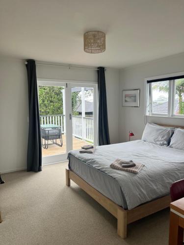 a bedroom with a large bed and a balcony at Studio 35 Kerikeri in Kerikeri