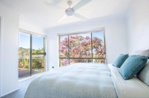 a white bedroom with a bed and a large window at Sapphire House in Mirador