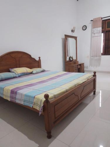 a bedroom with a bed with a wooden frame and a mirror at Green Haven by Gapper Sri Lanka in Wattala
