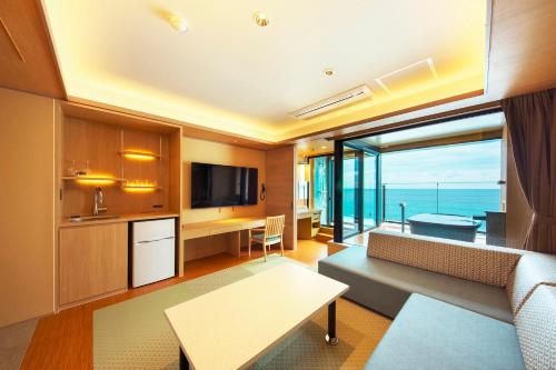 a living room with a couch and a kitchen with a large window at Senoumi in Higashiizu