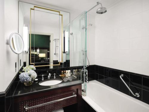 a bathroom with a sink and a tub and a mirror at Sofitel London St James in London