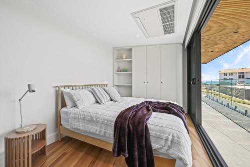 a bedroom with a bed and a balcony at Mirani's Penthouse in Port Adelaide