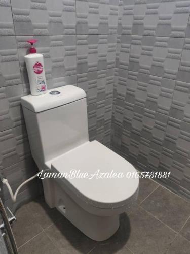 a white toilet in a bathroom with a wall at Laman Biru Azalea in Pekan