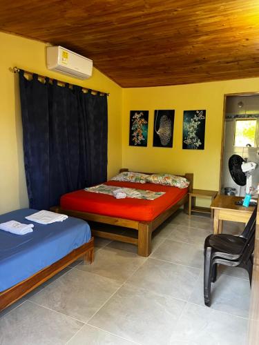 a bedroom with two beds and a desk and a chair at Cabañas Cambaro in Puerto Escondido