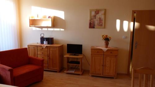 a living room with a chair and a computer on a cabinet at Apartmány Bea Donovaly in Donovaly